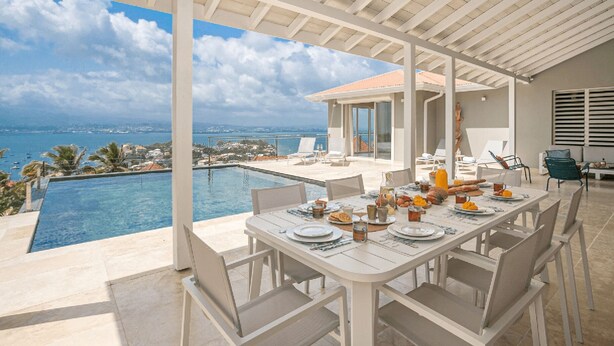 A dining area with a view of the sea and a pool.