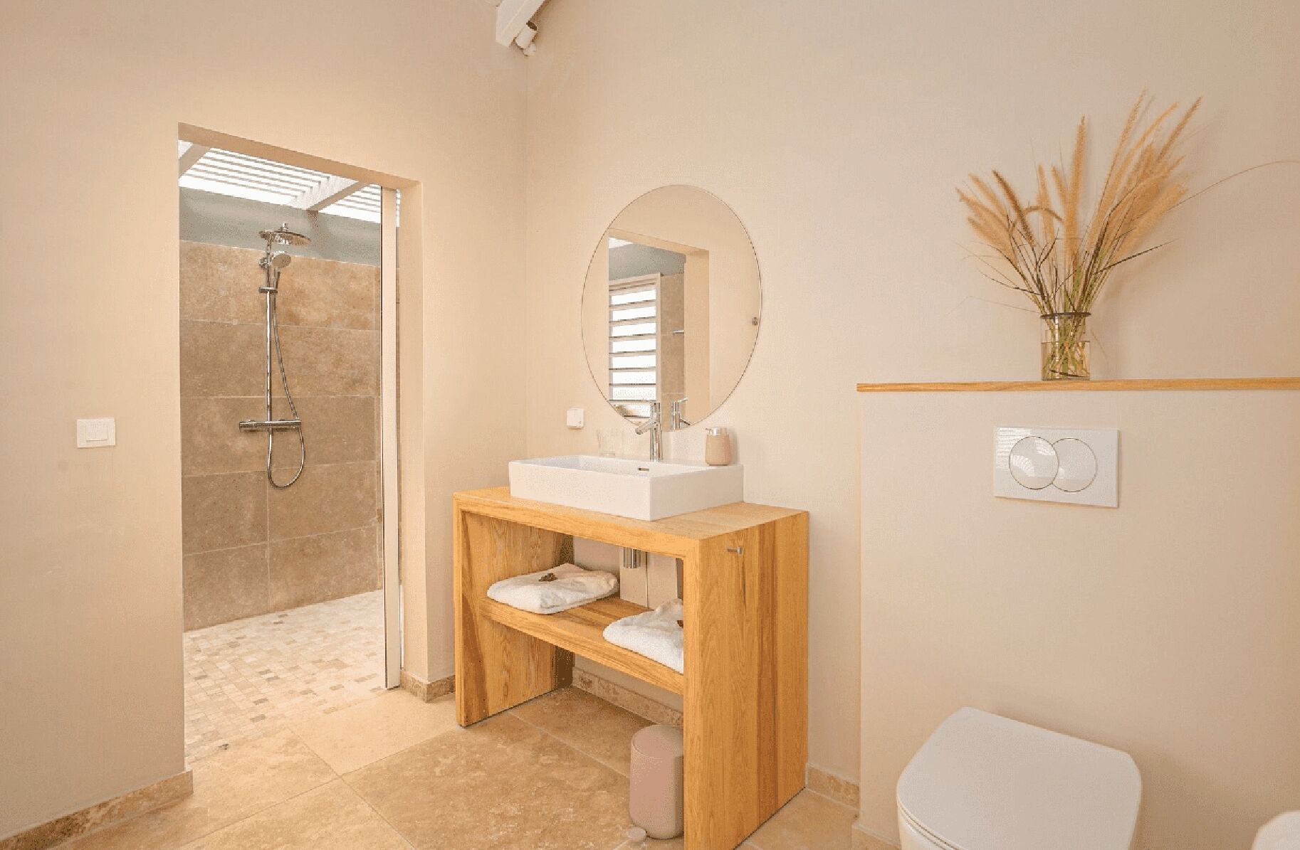 A modern bathroom with a shower, a sink with a mirror, and a toilet.