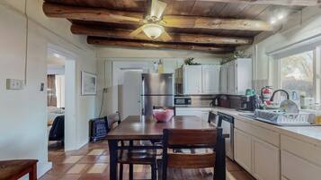 Una cocina con techo de madera, una mesa de comedor con sillas, un refrigerador y una ventana con vistas.