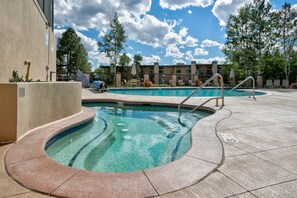 Relax by the pool surrounded by a spacious deck with a curved edge and metal handrails.