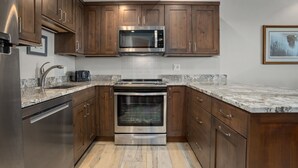 Una cocina moderna con armarios de madera, electrodomésticos de acero inoxidable y encimera de granito.