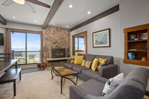 Relax in this stylish living room with a fireplace, balcony, and sofa, perfect for unwinding.