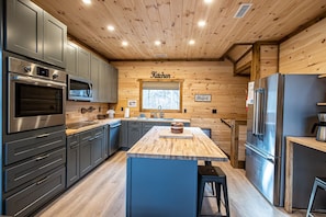 A modern kitchen with wooden walls, stainless steel appliances, and a central island.