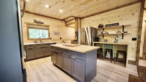 A kitchen with a wooden ceiling, a stainless steel refrigerator, and a coffee bar.