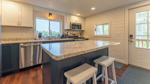 A modern kitchen with a large island, stainless steel appliances, and wooden cabinetry. - Yacht Club cabin on Burntside, with sauna (Ely)