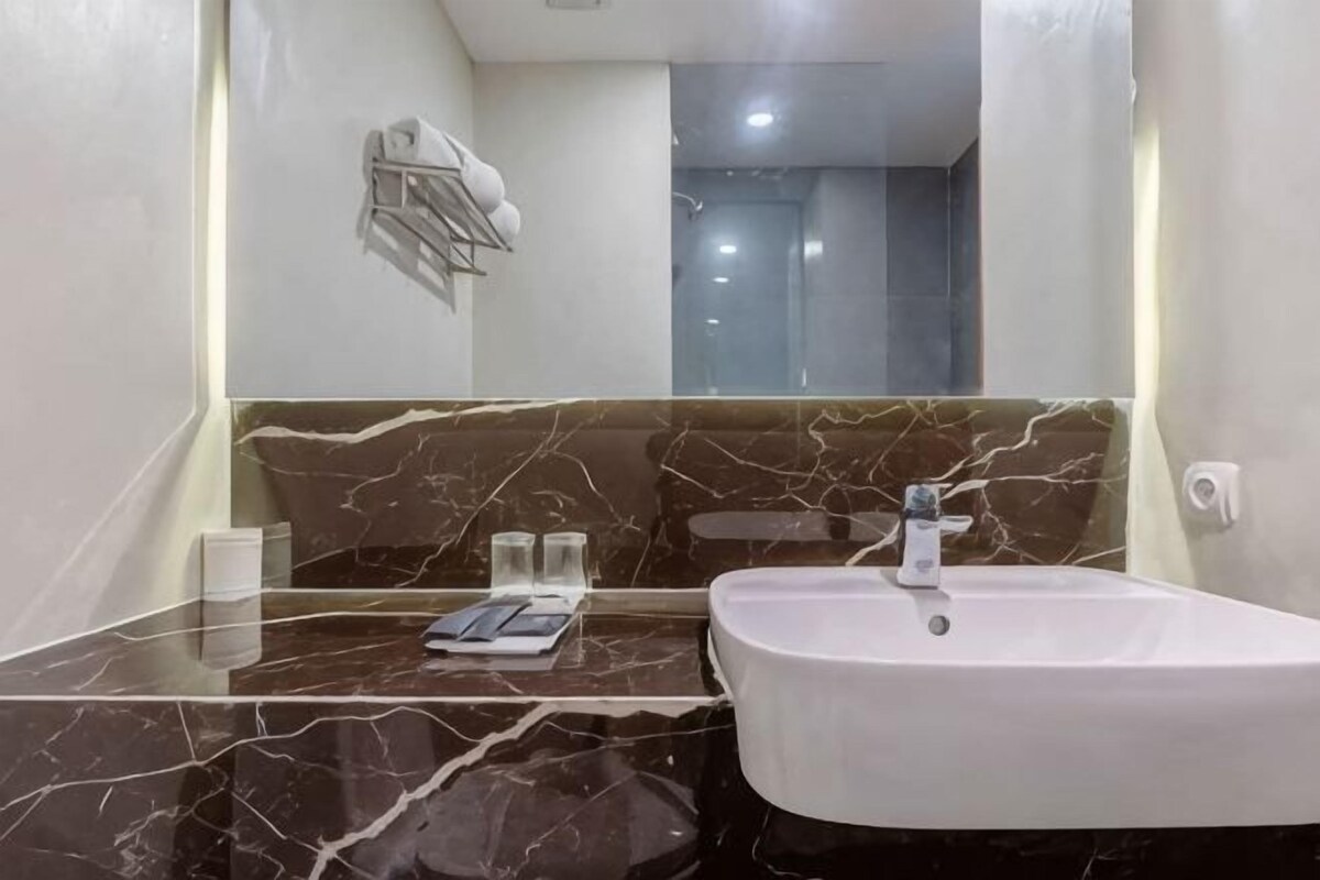 A bathroom with a marble countertop, a white sink, and a mirror.