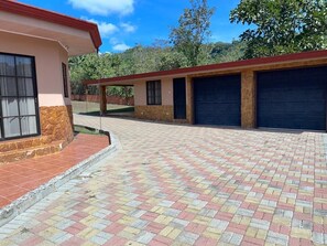A building with a paved driveway, a garage, and a covered area.