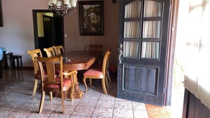 Un coin repas avec une table et des chaises en bois, un lustre et une porte avec des rideaux.