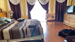 Une chambre d’hôtel avec un grand lit, une chaise, une commode et un téléviseur.