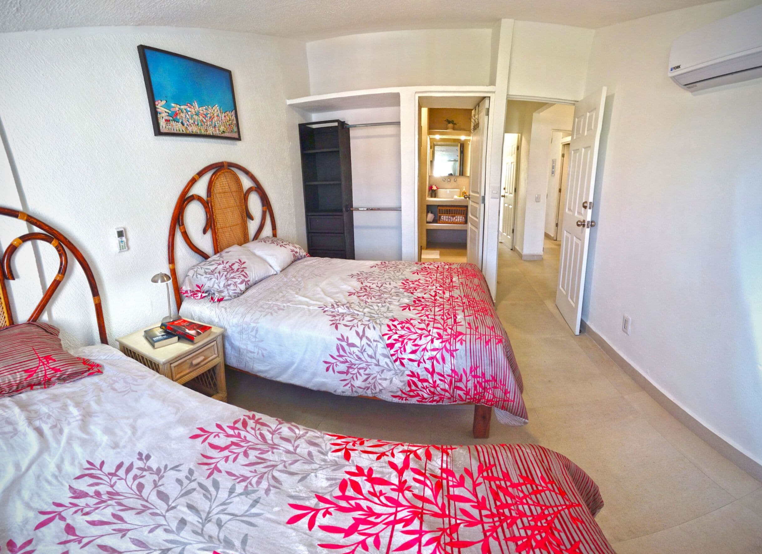 A bedroom with two beds, a wardrobe, and a bathroom visible through an open door.