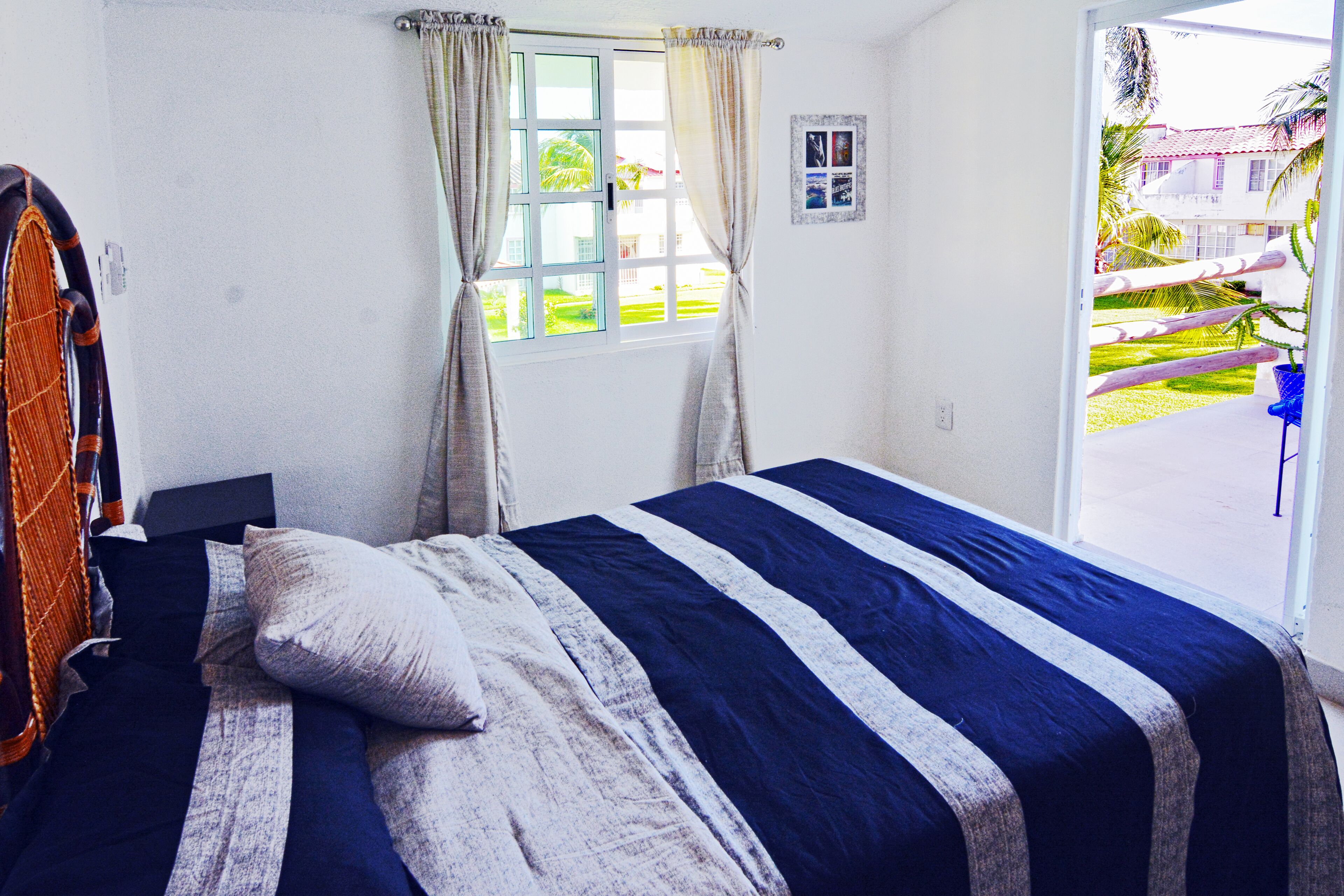 Un dormitorio con cama, cortinas, una ventana y vista a un jardín.