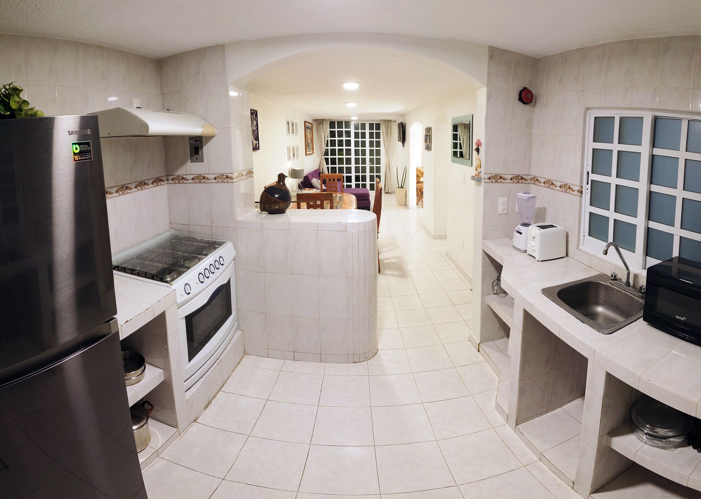 Una cocina moderna con una isla central, horno empotrado y un refrigerador de acero inoxidable.