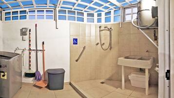 A bathroom with a shower, sink, and a hand dryer.