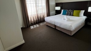 A hotel room with a large bed, a nightstand, a lamp, and a window with curtains. - Darwin Esplanade Central (Darwin)