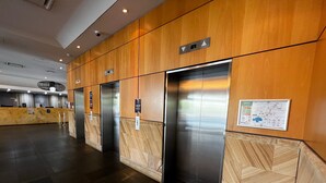 A modern elevator area with three elevators, a reception desk, and a floor plan sign on the wall. - Darwin Esplanade Central (Darwin)