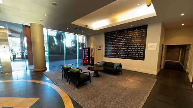 A modern lobby with a seating area, a large window, and a wall with motivational quotes. - Darwin Esplanade Central (Darwin)