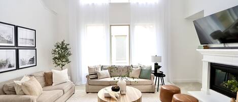 A living room with a sofa, armchairs, a coffee table, and a television.
