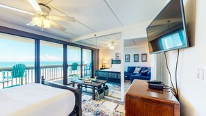 Une chambre d’hôtel avec un balcon, un lit, un bureau, une télévision et un canapé.