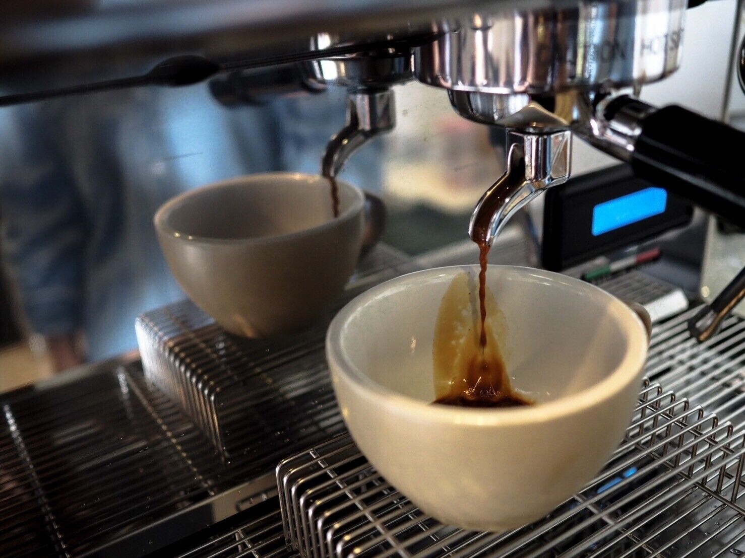 Una cafetera sirviendo espresso en una taza.