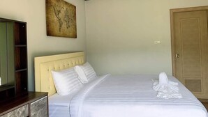 Habitació d'hotel amb un llit, una porta de fusta, un quadre a la paret i un televisor sobre un suport.
