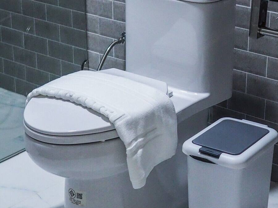 A toilet with a white lid and a white tissue box beside it.