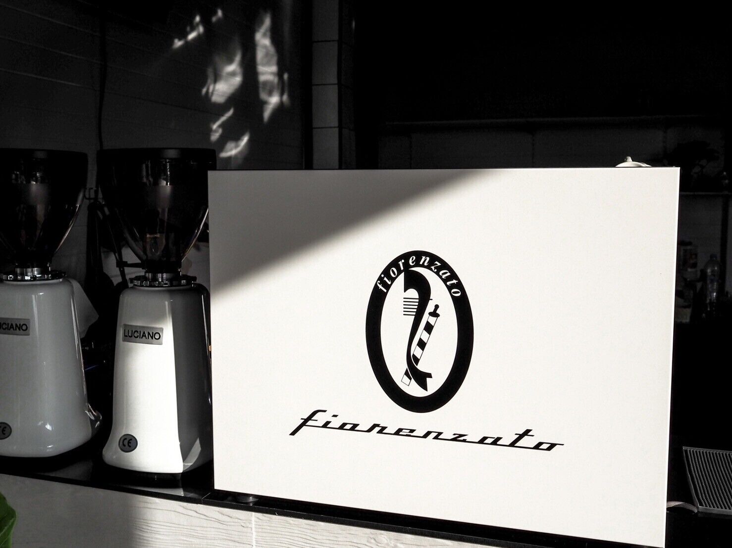 A kitchen counter with two blenders, a white sign with the logo and name "fiorenzato".