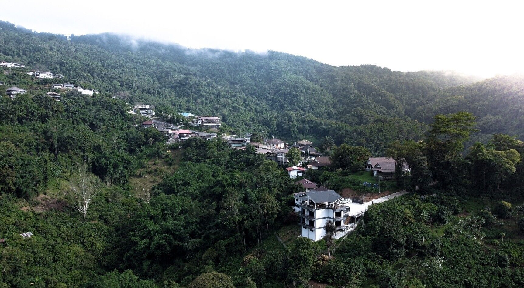 A hillside village with traditional houses and a modern building with a flat roof.