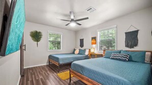 A bedroom with two beds, a ceiling fan, and a window with blinds.
