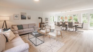 Amplia sala de estar con sofá, mesa de centro y comedor con sillas y una mesa.