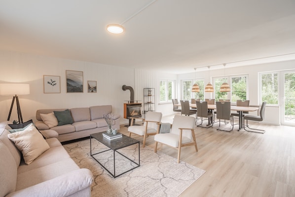 A spacious living room with a sofa, coffee table, and dining area with chairs and a table.