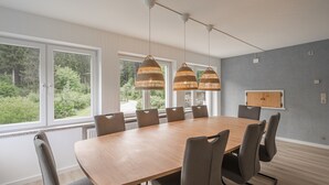 Un comedor moderno con una mesa grande, seis sillas y tres lámparas colgantes.