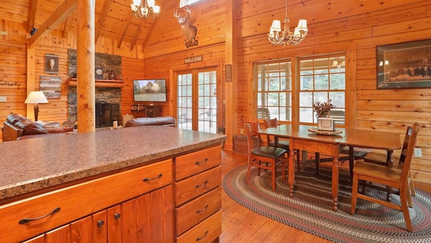 A log cabin interior with a kitchen, dining area, and living room. - Family Cabin on 20 Private Acres • Game Room • Near Berkeley Springs (Hancock)