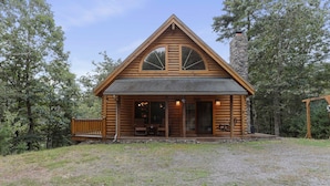 A log cabin with a stone chimney, large windows, and a porch with outdoor seating. - Family Cabin on 20 Private Acres • Game Room • Near Berkeley Springs (Hancock)