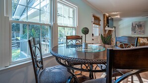 A dining area with a round glass table, surrounded by chairs, large windows, and a view of the backyard. - 4BR Cozy Home, Close to UGA & Downtown Athens (Athens)