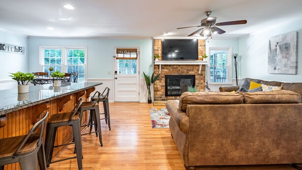 A modern kitchen with a bar area, a fireplace, and a seating area with a sofa and chairs. - 4BR Cozy Home, Close to UGA & Downtown Athens (Athens)