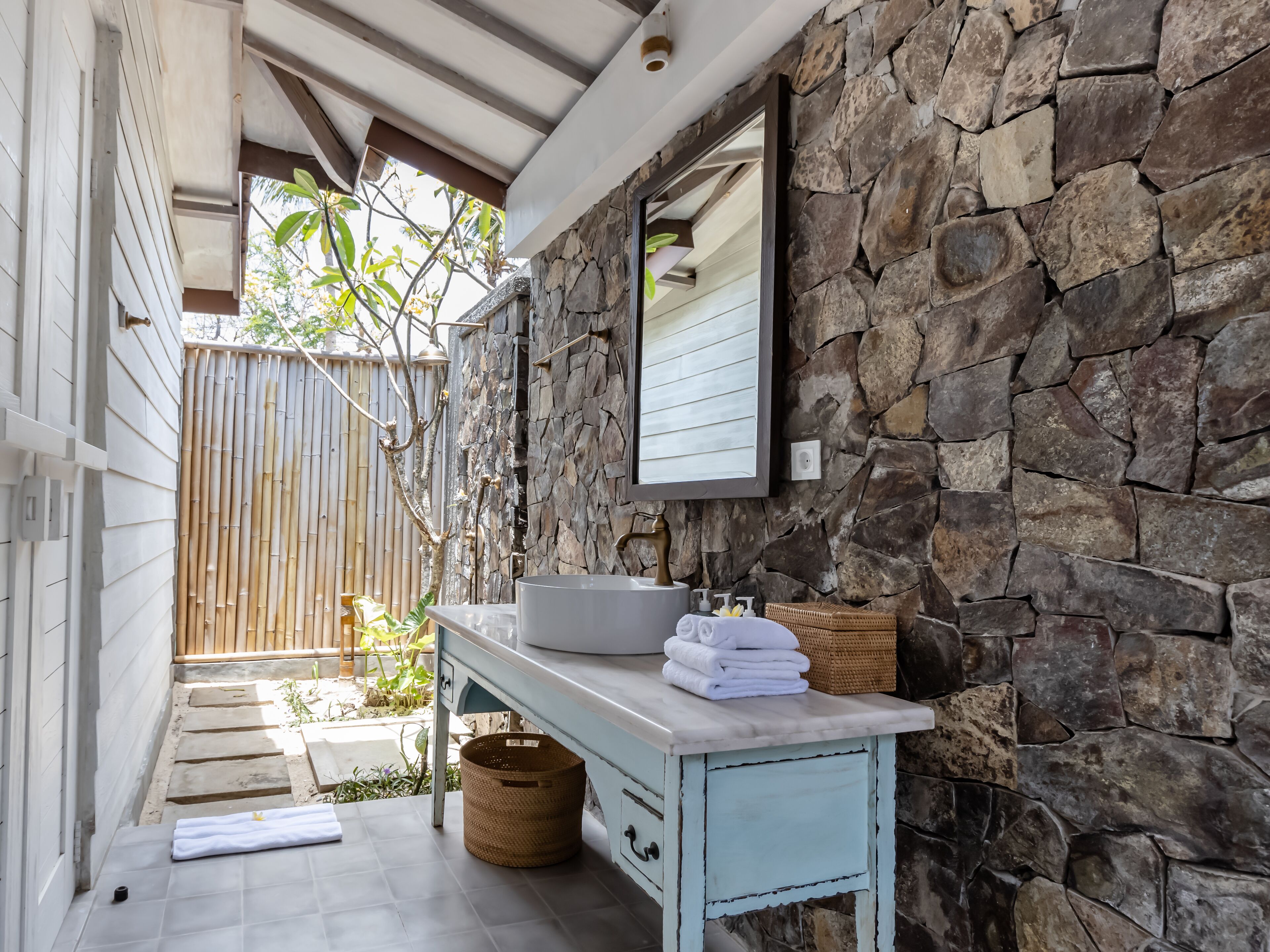 A bathroom with a stone wall, a sink, and a mirror.