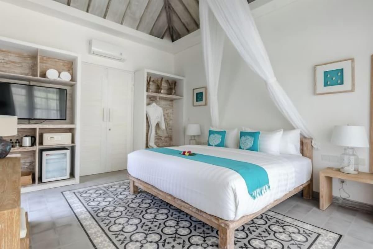 A bedroom with a bed, a TV, a wardrobe, and a bedside table.