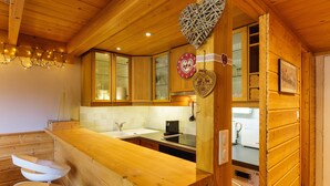 L’intérieur d’une cabane en bois comprend un coin cuisine, des placards en bois, un évier et un lave-linge.