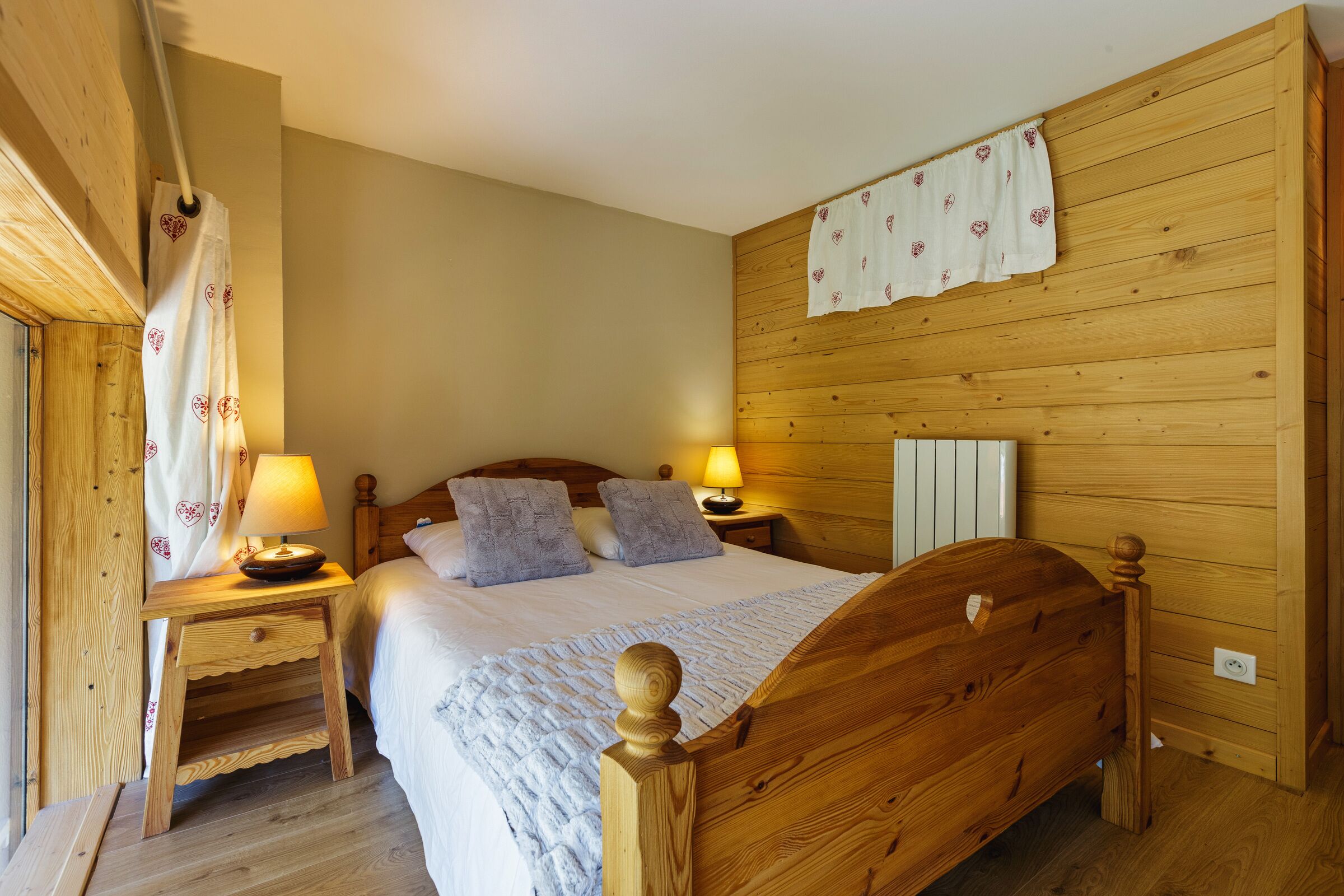 Ein Schlafzimmer mit Holzwänden, einem Bett, zwei Nachttischen und einem Beistelltisch.