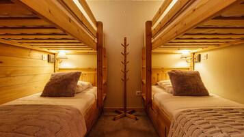 Une chambre avec deux lits, des murs en bois et un porte-manteau central.