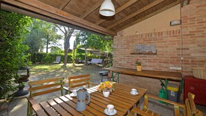 A wooden table with benches, a brick wall, and a hanging light fixture. - Casa Guna, Asciano, Italy (Asciano)