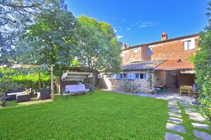 Une cour avec une pelouse, du mobilier d’extérieur et un bâtiment en briques surmonté d’un toit en tuiles.