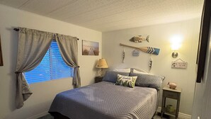 A bedroom with a large bed, a window with curtains, a nightstand, a lamp, and wall decorations including fish and a sign. - Water Front/ Lake Okeechobee Access in Buckhead Ridge (Okeechobee)