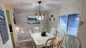 A dining area with a table and chairs, a chandelier, and a view of the outdoors through a window. - Water Front/ Lake Okeechobee Access in Buckhead Ridge (Okeechobee)