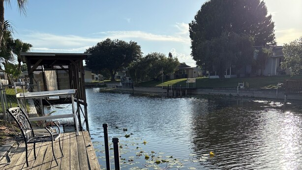 A wooden dock with chairs and a table, a calm lake with lily pads, and a clear sky. - Water Front/ Lake Okeechobee Access in Buckhead Ridge (Okeechobee)