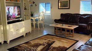 A living room with a television, a brown leather couch, a dining table, and a patterned rug. - Water Front/ Lake Okeechobee Access in Buckhead Ridge (Okeechobee)