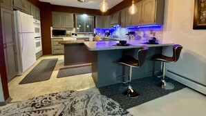 Una cocina moderna con una isla central, taburetes de bar e iluminación colgante.