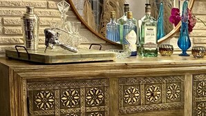 Una sala de estar con pared de ladrillo, un espejo redondo, un mueble con motivos decorativos y un sofá.