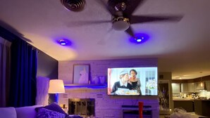 Una sala de estar moderna con televisor de pantalla plana, ventilador de techo y sofá.