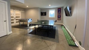 Una habitación con mesa de fútbol de mesa, mesa de ping pong y dardos.